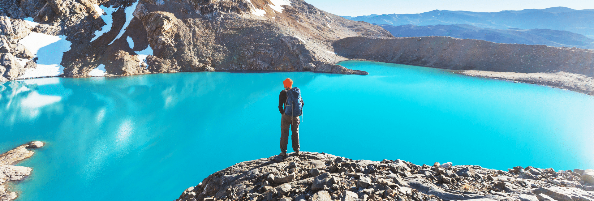 Hiker standing on a cliff overlooking a lake in Patagonia