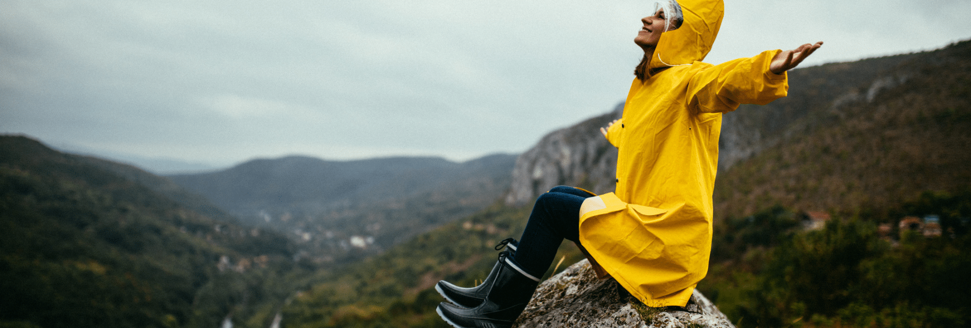 woman in rain coat on mountain with boots