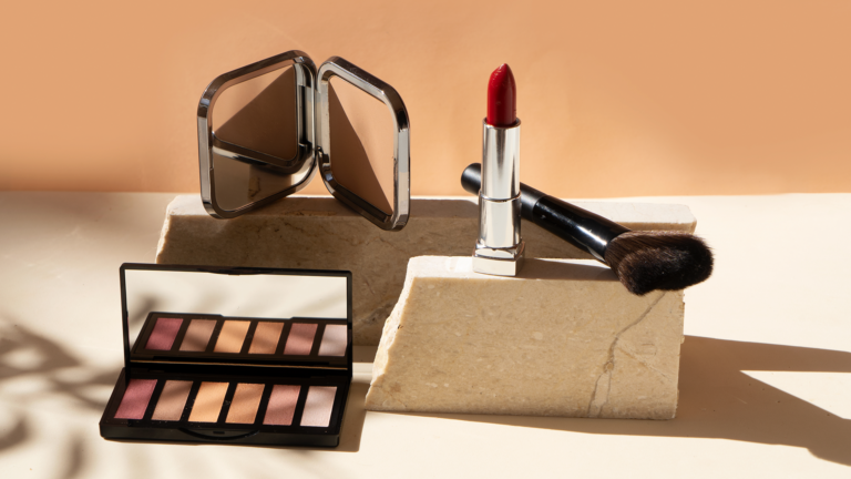 eyeshadow, lipstick, and brush on a stone surface